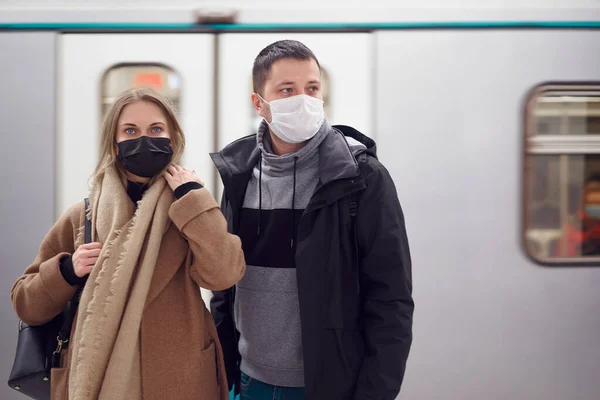 Hombre y mujer con máscaras médicas de pie junto al vagón del metro . — Foto de Stock