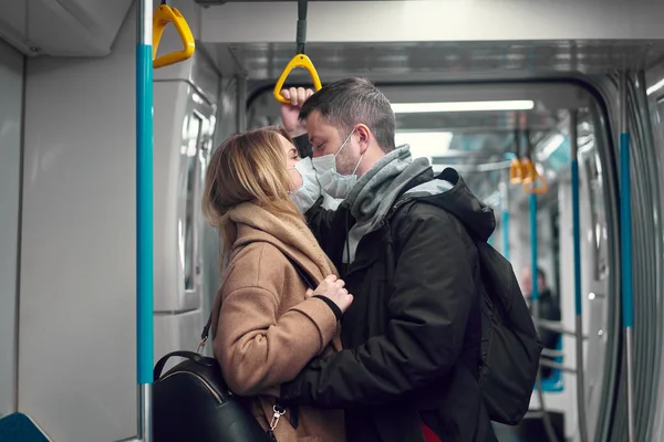 Young loving couple in medical masks hugging in subway. — Stock Photo, Image