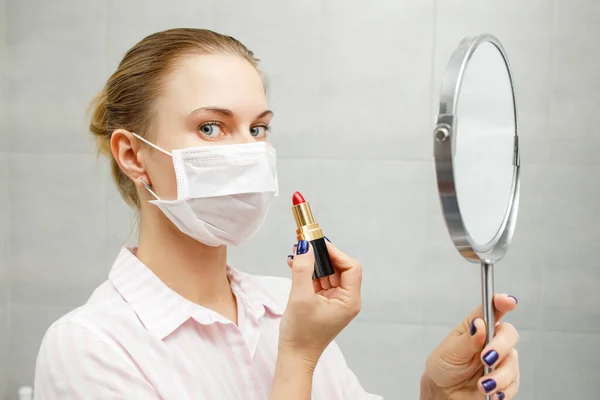 Primer plano de la mujer en máscara médica con lápiz labial y espejo en la mano — Foto de Stock