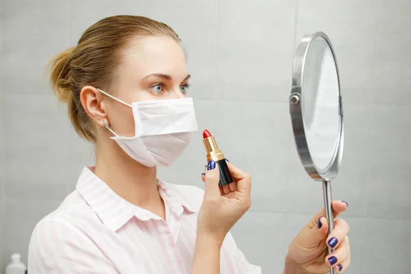 Primer plano de rubia en máscara médica con lápiz labial y espejo en la mano — Foto de Stock