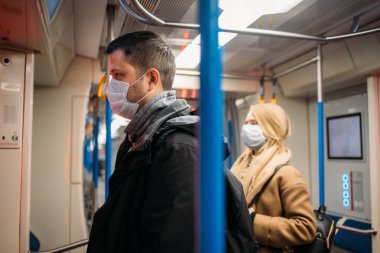 Metrodaki tırabzanların yanında duran genç adam ve kadın..