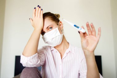 Tıbbi maskeli termometreyle yakın plan kadın. Coronavirüs salgını