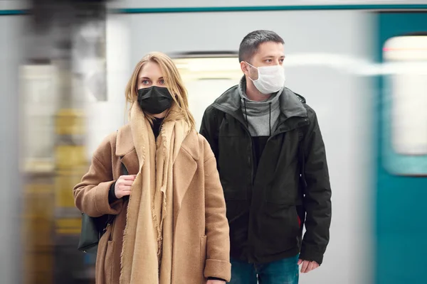 Брюне чоловік і блондинка, дивлячись на бік медичних масок, стоять біля машини в метро.. — стокове фото
