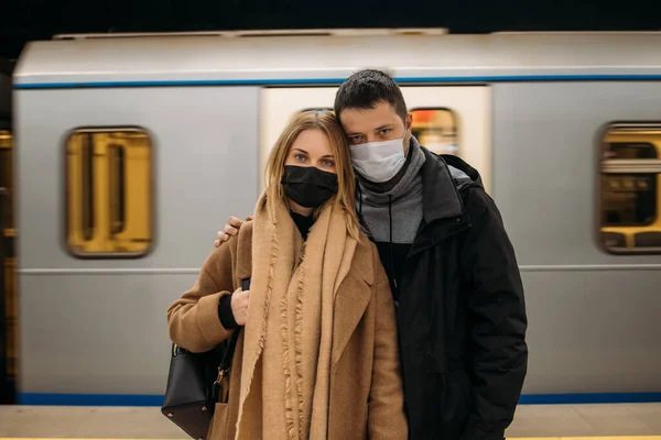 Молодий чоловік і жінка в масках стоять на тлі вагонів метро  . — стокове фото