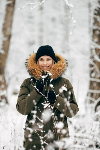 Ung kvinna på bakgrund av snöiga träd på promenad i vinterskogen — Stockfoto