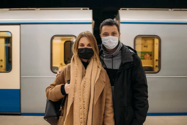 Крупним планом чоловік і жінка в масках стоять на тлі вагонів метро . — стокове фото