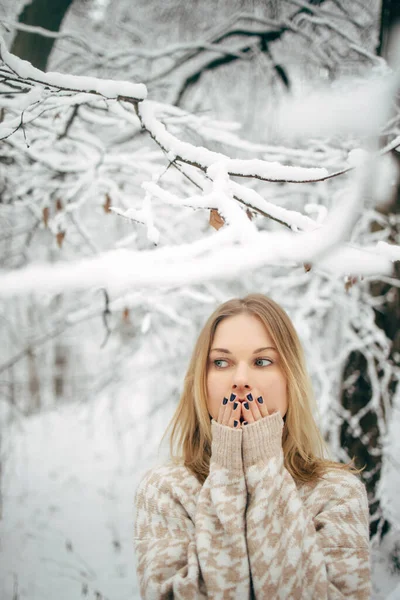 Ung kvinna med handflator nära ansiktet på bakgrund av snöiga träd för promenad i vinterskogen — Stockfoto