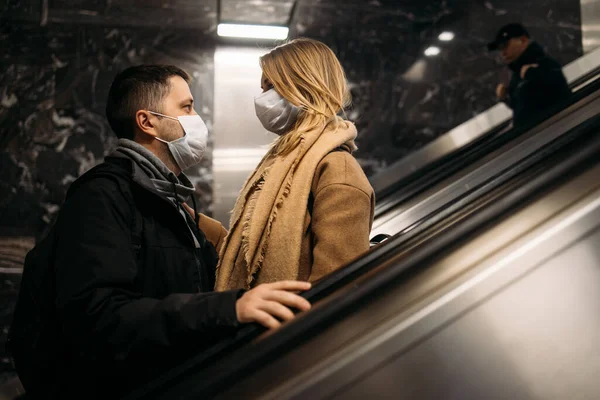 Чоловік і жінка дивляться один на одного в медичних масках на ескалаторі в метро . — стокове фото