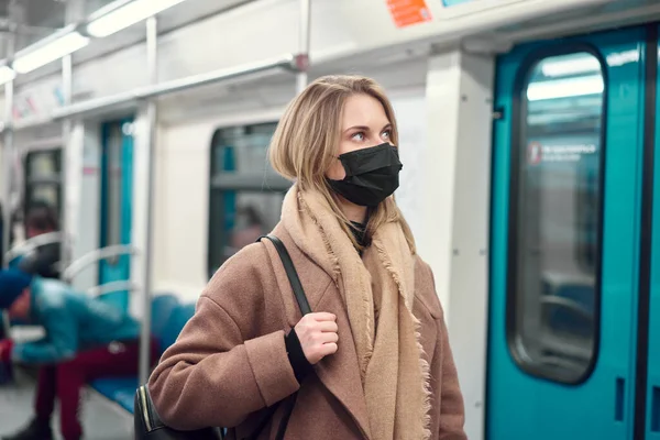 馬車の近くの地下鉄に立っている黒い医療用マスクの女性。コロナウイルスの流行. — ストック写真