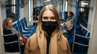 Girl in black medical mask standing in subway car. clipart