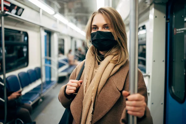 地下鉄車の中で手すりを保持医療マスクのブロンド. — ストック写真