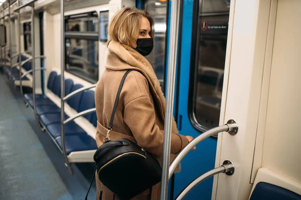 Молода блондинка в медичній масці тримає поручень в машині метро . — стокове фото
