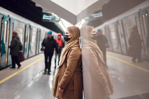 Mujer rubia con máscara médica negra parada en el metro cerca del carruaje . — Foto de Stock