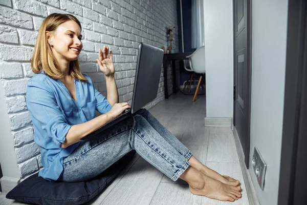 Красива бізнес-леді в повсякденному житті використовує ноутбук і посміхається, сидячи на підлозі вдома і працюючи — стокове фото