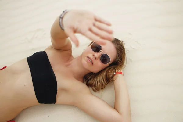 Mujer rubia en traje de baño acostada en la playa de arena —  Fotos de Stock