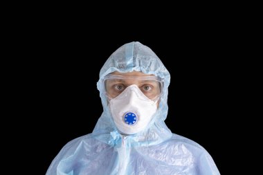 Beyaz koruyucu giysili, maskeli, siyah arka planda gözlüklü ve eldivenli bir adam, koronavirüs salgını tehdidi. Salgın, Coronavirus covid 19 salgını. Doktor, hasta solunum cihazında..
