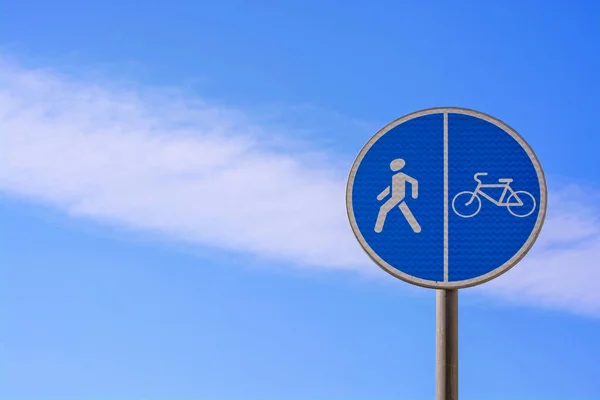Στρογγυλή μπλε πινακίδα Πεζόδρομος και ποδηλατόδρομος με συνδυασμένη διαδρομή στο φόντο ενός όμορφου συννεφιασμένου ουρανού — Φωτογραφία Αρχείου