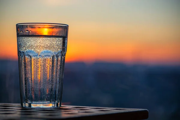 Glass of sparkling water at sunset. Summer evening — Stock Photo, Image