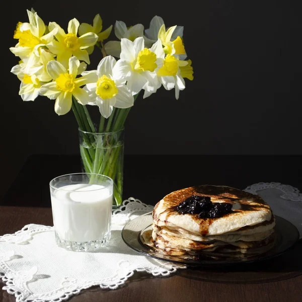 Pilha de panquecas na mesa de madeira preta com amarelo e vidro de leite — Fotografia de Stock