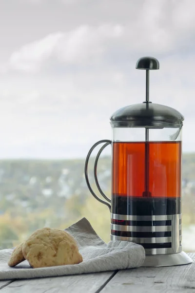 Черный чай в чашке и чайник с печеньем на деревянном фоне — стоковое фото