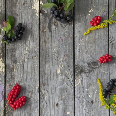 Eski ahşap arka planda böğürtlen ve çiçek kasesi. Seçici odaklanma. Metin için boşluk.