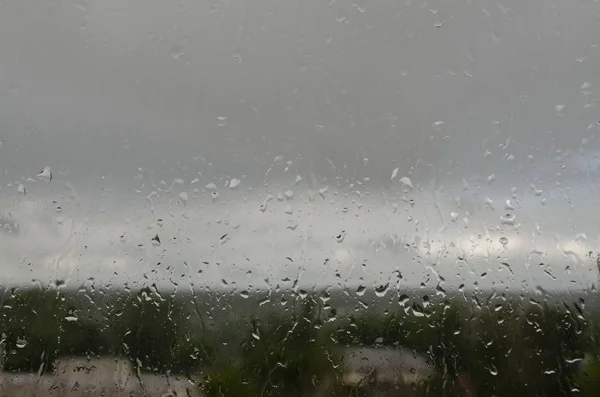 회색빛 하늘을 배경으로 유리에 비친 빗방울 — 스톡 사진