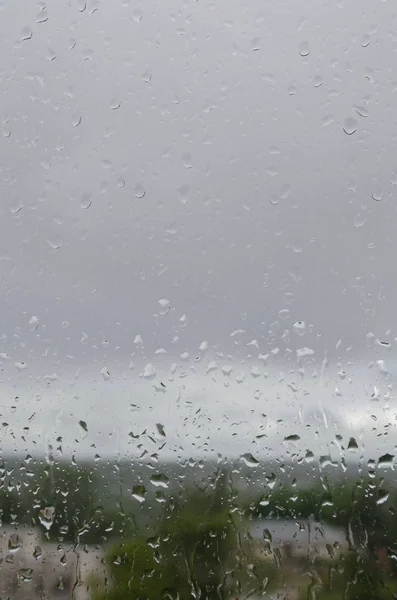 Gocce di pioggia su vetro contro un cielo grigio — Foto Stock