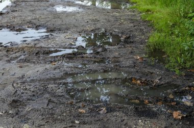 Çamur ve su birikintileriyle dolu bir toprak yol, ilk buzlar, kırsal bölgelerdeki sorunlu yollar..