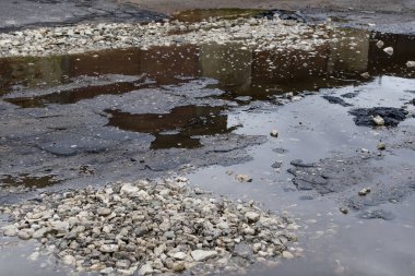 Büyük bir çukur ve su birikintisi ile şehirde Asfalt yol