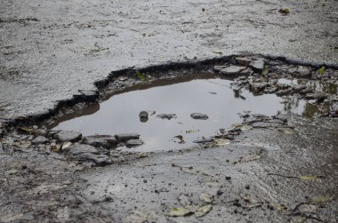 Büyük bir çukur ve su birikintisi ile şehirde Asfalt yol