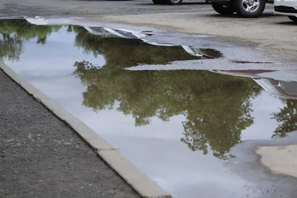 Gropar och pölar vid trottoaren. Subsistans på vägen. Reparation krävs. — Stockfoto