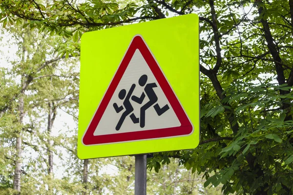 Attenzione bambini cartello stradale su sfondo alberi — Foto Stock