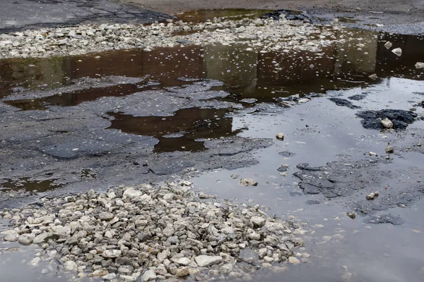 Büyük bir çukur ve su birikintisi ile şehirde Asfalt yol