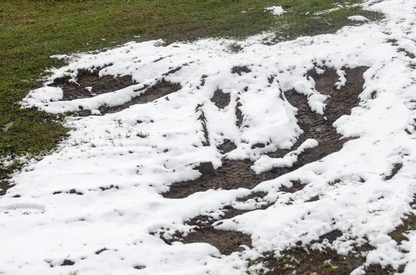 Zimna trawa. Ścieżki ciągnika przez pokrytą śniegiem trawę zimą — Zdjęcie stockowe