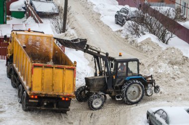 Traktör karları şehirden çıkarmak için kamyona yüklüyor.