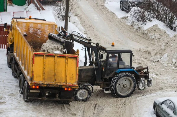 Traktör karları şehirden çıkarmak için kamyona yüklüyor.
