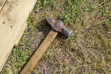 Eski antika çekiç. Yeryüzünün arka planında çimenler ve tahtalar var.