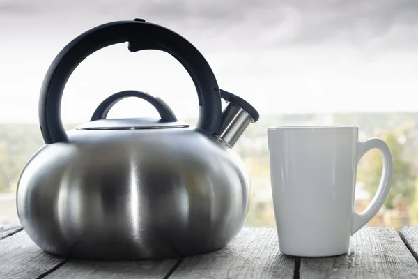 Стальной чайник и кружка. Горячий утренний чай в белой кружке и киле на деревянном столе для завтрака — стоковое фото