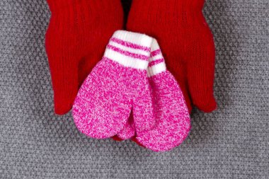 Kadınların kırmızı eldivenlerindeki çocukların küçük eldivenleri. Annelik ve sevgi kavramı