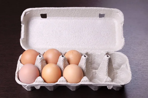 Cardboard egg rack with six red eggs and 4 empty cells