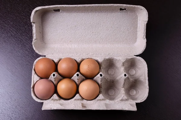 Cardboard egg rack with six red eggs and 4 empty cells
