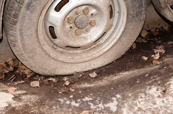 A flat tire in a car splattered with gravel and sand