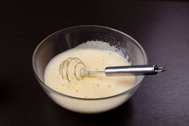 Cam bir tabakta çırpılmış yumurta ve metal çırpılmış çırpılmış
