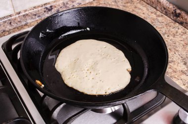 Gaz sobasında, dökme demir tavada kızartılmış gözleme.