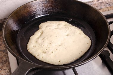 Gaz sobasında, dökme demir tavada kızartılmış gözleme.