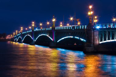 Saint Petersburg 'daki gece manzarası, Trinity köprüsü ve parlak ışıklardan yansıyan suda güzel bir yansıma..