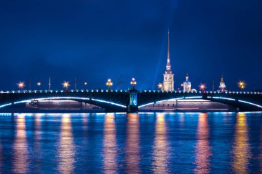 Saray köprüsü ve Saint-Petersburg 'daki Peter ve Paul kalesi. Parlak ışıklar suya yansıyor.