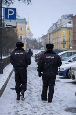 Rusya 'da iki polis memuru karlı sokaklarda devriye geziyor. Bir adam önde yürüyor. Çevirisi: Polis