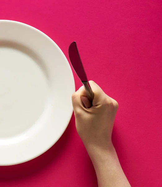 Fork and knife in hands on red background with white plate — 图库照片
