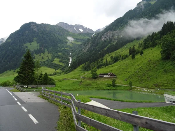 Las verdes montañas de Austria son carretera y valla. Las verdes montañas de Austria son carretera y valla. Niebla desciende de las montañas — Foto de Stock